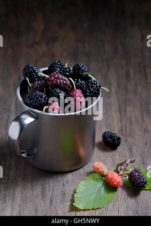 Maulbeeren in Metall Becher auf hölzernen Hintergrund Stockfoto