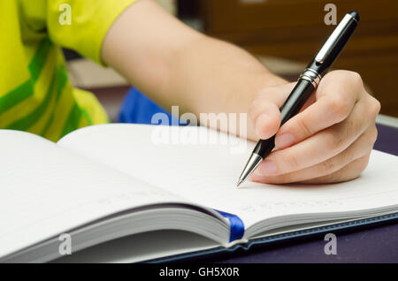 Write-Aktivität (eine Mädchen Hand hält einen Stift und schreiben auf ein Buch) Stockfoto
