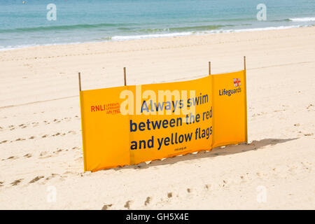 RNLI Rettungsschwimmer Sicherheitsbanner schwimmen im Juni immer zwischen den roten und gelben Fahnen am Bournemouth Beach, Bournemouth, Dorset UK Stockfoto