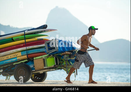 RIO DE JANEIRO - 5. April 2016: Junge Carioca brasilianischen Mann zieht einen Karren von Stand up Paddle SUP Surfboards. Stockfoto