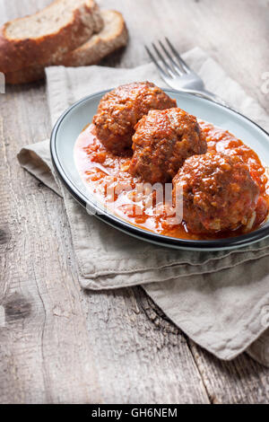 Fleischbällchen in Tomatensauce, Brot auf alten hölzernen Hintergrund Stockfoto