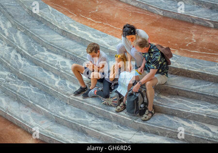 Eine Familie von Touristen sitzen auf dem geschwungenen Marmor Schritte in den Wintergarten Atrium von Brookfield Place in Lower Manhattan Stockfoto