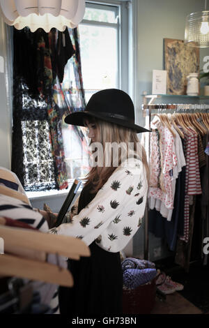 12 Jahre altes Mädchen trägt einen schwarzen Hut in einem Vintage-Kleidung Shop durchsuchen Stockfoto