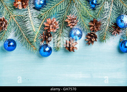 Weihnachten oder Neujahr Hintergrund: Tannenzweigen, blauen Glaskugeln und Tannenzapfen über Türkis hölzernen Hintergrund Textfreiraum Stockfoto