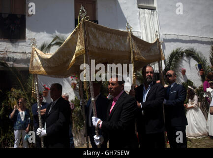 Männer halten einen Sonnenschirm in Corpus Christi fest in El Gastor, Sierra de Cadiz, Andalusien, Spanien Stockfoto