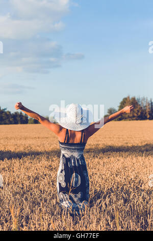Beauty Woman in einem Sommerkleid mit entspannten Sommerhut in Landschaft mit aufgehobenen Händen, Sommer-Konzept mit lösen applying Stockfoto
