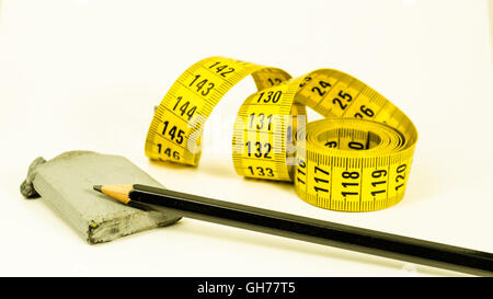 Stillleben mit einem gelben Maßband, ein schwarzer Stift und Kautschuk, über weiß Stockfoto