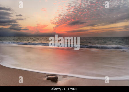 Ocean Sunset ist eine weiche Pastell farbigen Strandlage mit einem detaillierten Wolkengebilde und einer sanften Welle ans Ufer Rollen. Stockfoto