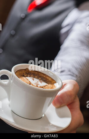Kellner serviert Kaffeetasse in der Nähe Stockfoto