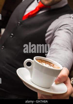 Kellner serviert Kaffeetasse in der Nähe Stockfoto