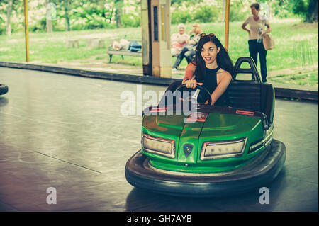 Süße junge Frau, die Spaß an Stoßstange Elektroauto im Vergnügungspark Stockfoto