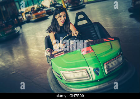 Süße junge Frau, die Spaß an Stoßstange Elektroauto im Vergnügungspark Stockfoto