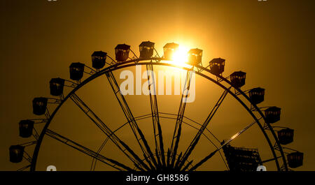 München, Deutschland. 8. August 2016. Die Sonne geht hinter einem Riesenrad im Olympiapark in München, Deutschland, 8. August 2016. Foto: SVEN HOPPE/Dpa/Alamy Live News Stockfoto