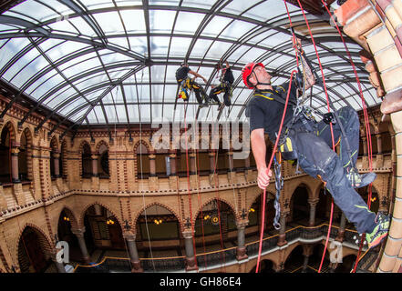 Rostock, Deutschland. 9. August 2016. Industriekletterer Andre Erdmann, Geschäftsführer der Firma Special Rope Access, reinigt das Glasdach im Ständehaus in Rostock, Deutschland, 9. August 2016. Die offizielle Residenz der höhere regionale Gericht (OLG) des Landes Mecklenburg-Vorpommern wurde zwischen 1889 und 1893 erbaut und vor einigen Jahren aufwändig restauriert. Das Glasdach des neugotischen Gebäudes Hertiage geschützt ist jetzt innen und draußen von der Firma Spezialität zum ersten Mal gereinigt worden. Foto: JENS Büttner/Dpa/Alamy Live News Stockfoto