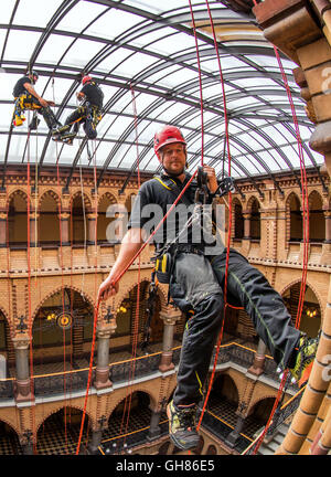 Rostock, Deutschland. 9. August 2016. Industriekletterer Andre Erdmann, Geschäftsführer der Firma Special Rope Access, reinigt das Glasdach im Ständehaus in Rostock, Deutschland, 9. August 2016. Die offizielle Residenz der höhere regionale Gericht (OLG) des Landes Mecklenburg-Vorpommern wurde zwischen 1889 und 1893 erbaut und vor einigen Jahren aufwändig restauriert. Das Glasdach des neugotischen Gebäudes Hertiage geschützt ist jetzt innen und draußen von der Firma Spezialität zum ersten Mal gereinigt worden. Foto: JENS Büttner/Dpa/Alamy Live News Stockfoto