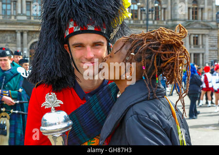 Glasgow, Vereinigtes Königreich. 9. August 2016. Am zweiten Tag des "Piping Lebens" parade der Bands The Royal Edinburgh Military Tattoo um George Square vor dem Betreten der Piping Live Arena für ein spektakuläres Feuerwerk. Das Bild ist von SAMAITA aus Kenia zeigt ihre Wertschätzung für die Unterhaltung zu JOE CARRIGAN aus Sydney, Australien-Credit: Findlay/Alamy Live News Stockfoto