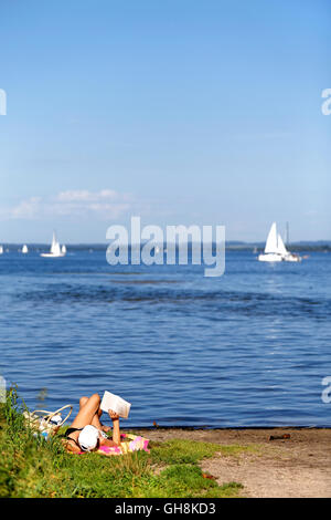 Frau Sonnenbaden am Strand, lesen eine Buch, Oberbayern, Deutschland, Europa. Stockfoto