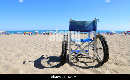 isolierte Rollstühle für Menschen mit Gehbehinderung am Meeresstrand Stockfoto