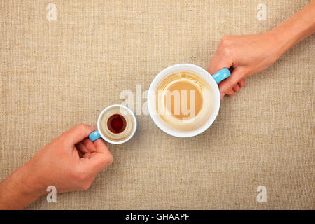 Zwei Hände, Mann und Frau, hält fertig leere Kaffeetassen, kleinen Espresso und große Latte Cappuccino, zusammen über Leinen canva Stockfoto