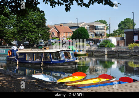 Chichester canal Bassin - bunten festgemachten Boote - schattigen Bäumen - Stadt Hintergrund - Tourist Kreuzfahrtschiff vorbei Stockfoto