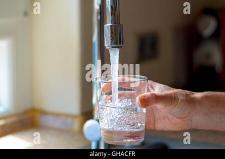Füllen ein Glas Wasser aus Edelstahl oder Chrom Wasserhahn oder Wasserhahn, Frau hautnah auf ihre Hand und das Glas mit fließendem w Stockfoto