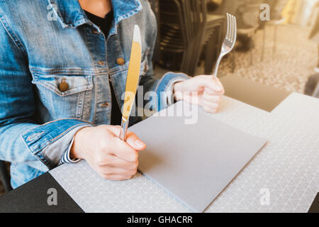 Hungrige Frau mit Messer und Gabel, warten auf Nahrung, Nahrung oder Restaurant-Konzept, Licht Warmton Stockfoto