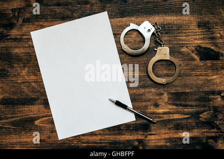 Polizeihandschellen und weißes Papier auf Ermittler Detektiv Schreibtisch, Konzept von Gesetz und Verbrechen. Stockfoto