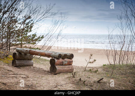 Leere grobe Holzbank steht auf Ostseeküste im Frühling. Küstenlandschaft Stockfoto