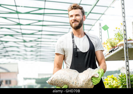 Schöne Gärtnerin mit Tasche des Bodens Stockfoto