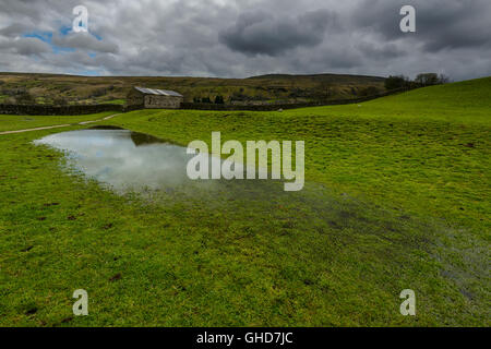 Überflutete Wiese in der Nähe von Muker, einer Ortschaft und einer zivilen Pfarrei am westlichen Ende von Swaledale in North Yorkshire, England, an einem übergiebelten Mai-Tag Stockfoto