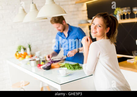 Frau trinkt Kaffee, während ein Mann eine Mahlzeit bereitet Stockfoto