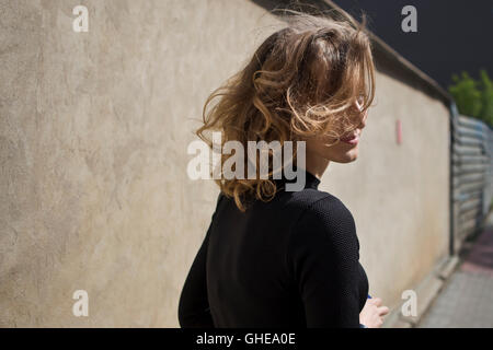 Schöne Frau mit einem ernsten Ausdruck auf ihrem Gesicht, Blick geradeaus mit Blick auf Industriegebiet im Hintergrund Stockfoto