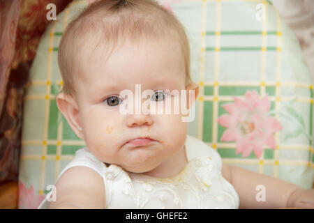 Kleines Kind Mädchen in einen Hochstuhl sitzt und isst cookies Stockfoto