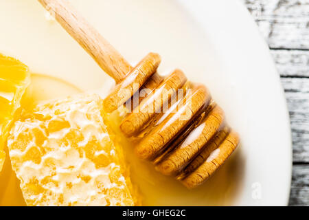 Hölzerne Honig-Stick und Waben auf Platte. Stockfoto