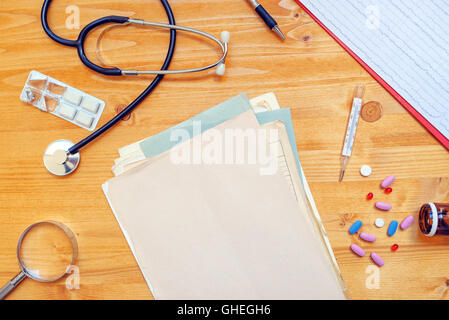 Sortierten Bürobedarf auf allgemeinen Arzt Schreibtisch. Arbeitsbereich des Arztes als Textfreiraum, Ansicht von oben. Stockfoto