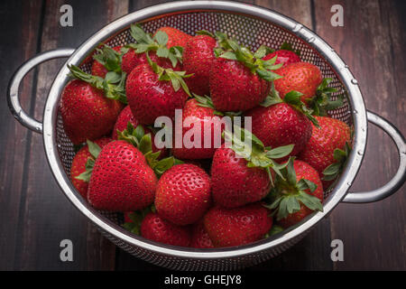 Frische Erdbeeren in Edelstahl Sieb auf eine Holzoberfläche Stockfoto
