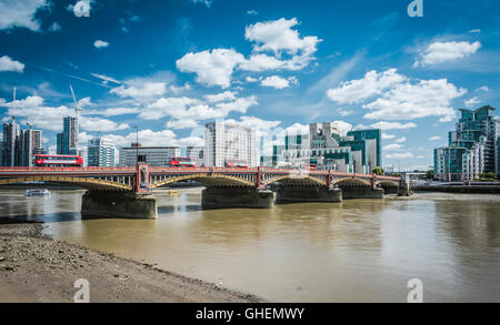 MI6 Hauptquartier (Vauxhall Cross) am Ufer einer schlammigen Themse mit roten TFL Routemaster Bussen, die über die Vauxhall Bridge, London, fahren Stockfoto