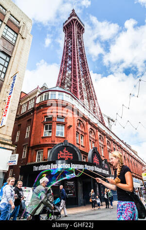 Junge weibliche Straßenkünstler Luftblasen unter der Blackpool Tower machen. Blackpool, Lancashire, England UK. Stockfoto