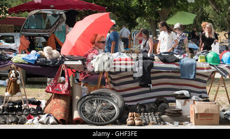 Ein Verkäufer bei einem Auto Boot Verkauf vide Grenier Unterstände unter einem Regenschirm oder Sonne Rotton auf einem glühend heißen Tag im Sommer in der Nähe von C Stockfoto