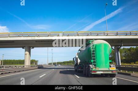 Green Cargo Tankwagen geht auf Asphalt Autobahn unter Betonbrücke, Rückansicht Stockfoto