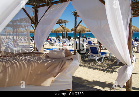 Outdoor-Massageliegen am White Sand Beach in einem Maya-Riviera Beachresort mit Blick auf das blaue Meer, Strand, Möbel und Hütten Stockfoto