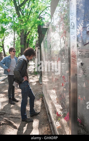 Oscar Wilde Grab Paris, Besucher zu Oscar Wildes Grab auf dem Friedhof Pere Lachaise lesen die Graffiti auf dem Plexiglas-Bildschirm um das Grab, Paris. Stockfoto