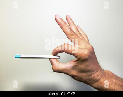 schlanke weiße Powerbank für das Telefon in der Hand auf dem isolierten Hintergrund Stockfoto