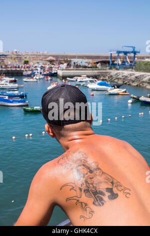 Einschiffung der Madonna, Nuestra Señora del Carmen auf einem Fischerboot beobachtet von einem jungen Mann mit Tattoo der Jungfrau und Stockfoto