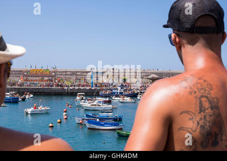 Einschiffung der Madonna, Nuestra Señora del Carmen auf einem Fischerboot beobachtet von einem jungen Mann mit Tattoo der Jungfrau und Stockfoto