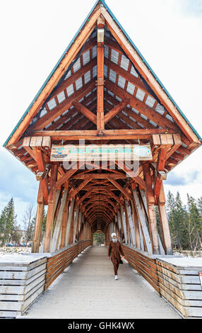 Mann geht über Kicking Horse Fußgängerbrücke über den Kicking Horse River in der Stadt des Kicking Horse, BC, Kanada. Stockfoto