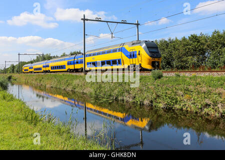 LISSE, Niederlande - 9. August 2015: niederländische gelbe und blaue Zug bewegen spiegelt sich in einem Kanal Stockfoto