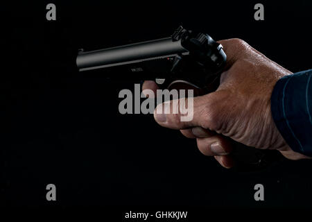 Pistole in der Hand des Mannes auf rosa Hintergrund Stockfoto