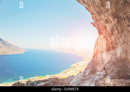 Kletterer auf einer Klippe gegen die malerische Aussicht auf Telendos Insel bei Sonnenuntergang. Insel Kalymnos, Griechenland, Illustrative Redaktion, Stockfoto