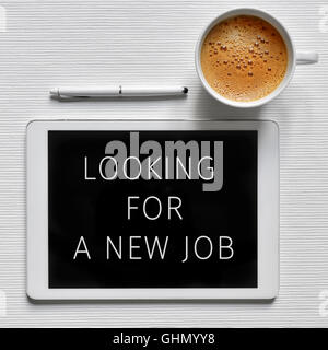 High-Angle Shot eines Tablet-Computers mit dem Text auf der Suche nach einem neuen Job in seinem Bildschirm, eine Tasse Kaffee und einem digitalen Stift auf einem w Stockfoto